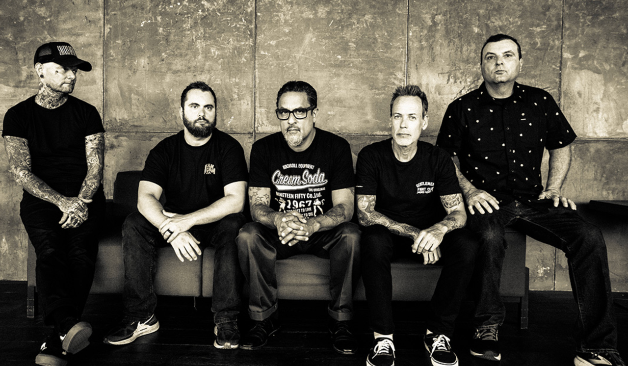 American punk rock band Strung Out members sitting together on a couch in a black and white promotional photo.